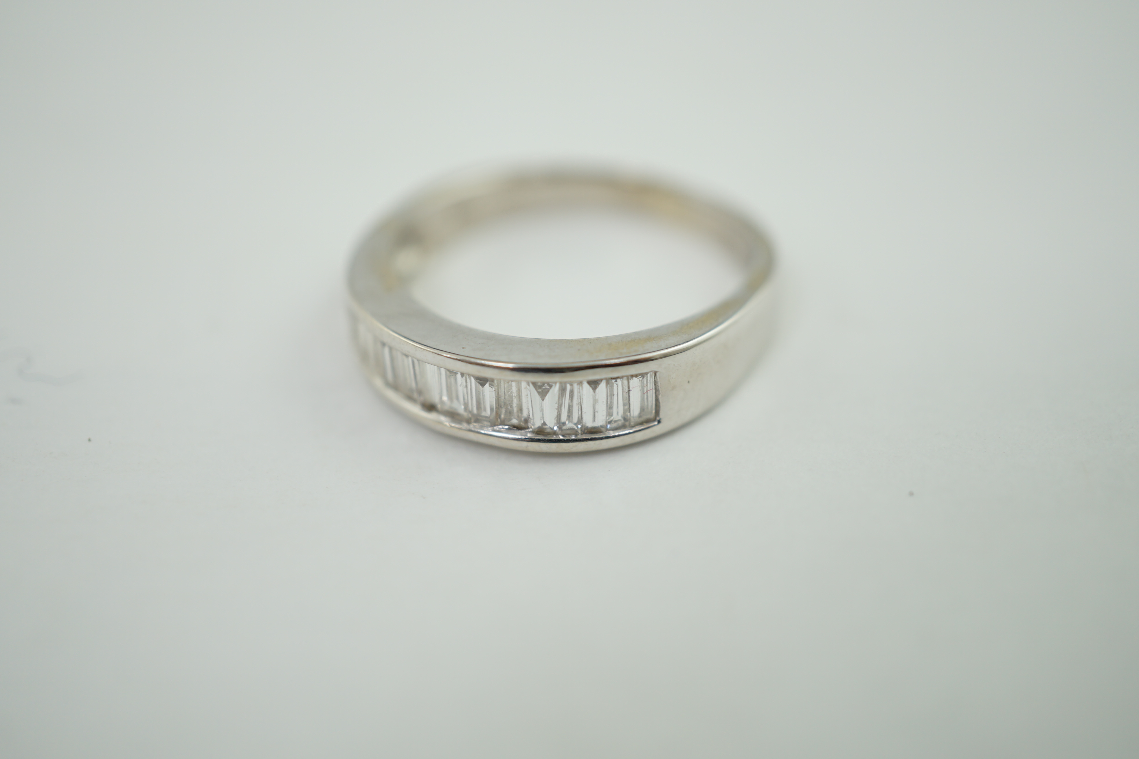 An 18ct white gold and baguette cut diamond channel set half eternity ring